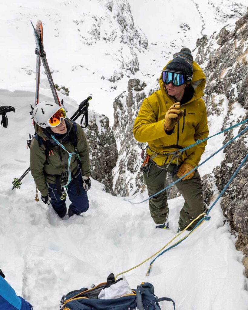 Bergführer erklärt das Abseilen mit Skis in ein Couloir